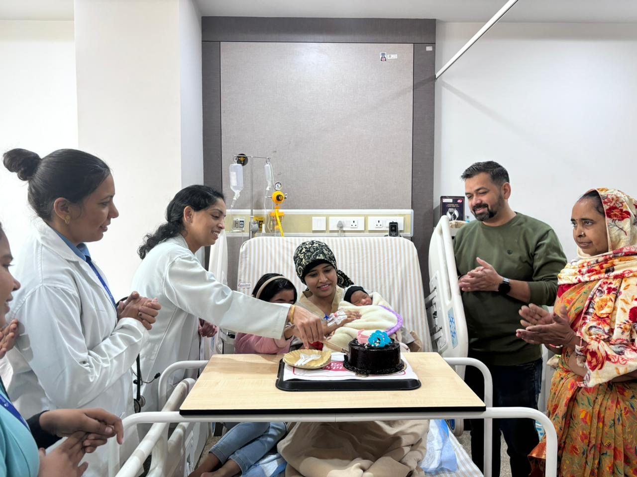 Happy mother and newborn celebrating with Dr. Pooja Chitlangia's team